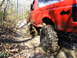 1994 Ford F-250 - This red 1994 Ford F-250 navigates a muddy trail, its off-road capabilities.