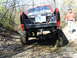 1994 Ford F-250 - Red 1994 Ford F-250 with large off-road tires navigating a muddy trail.