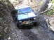 1994 Ford F-250 - Jeep Cherokee XJ struggles through a muddy off-road obstacle with a tree blocking the path.