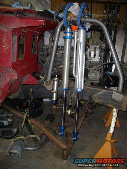 Custom off-road suspension with dual shocks and coilover setup mounted to a red vehicle frame