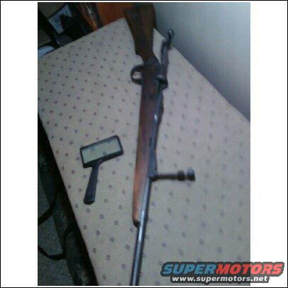 Old rifle and a small black electronic device with a screen on a patterned surface