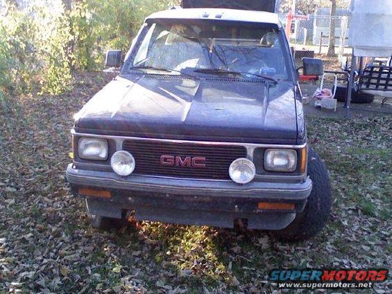 Dark blue GMC pickup truck front view, with aftermarket lights and a red GMC grille emblem
