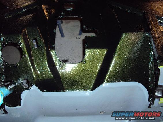Green painted vehicle undercarriage with a large opening and some light gray primer