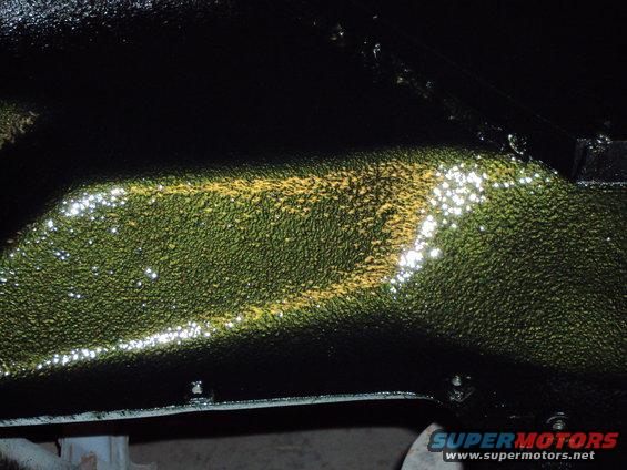 Underside of vehicle frame with textured green and yellow paint