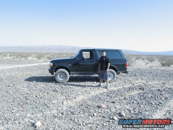 Guy standing next to black Ford Bronco in a rocky desert landscape