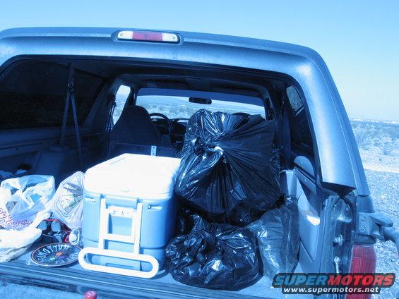 SUV cargo area filled with black trash bags and a white cooler