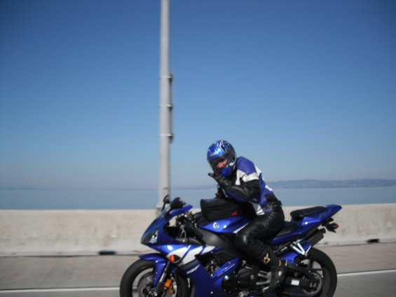 Blue sport motorcycle with rider wearing blue and black gear, on a bridge