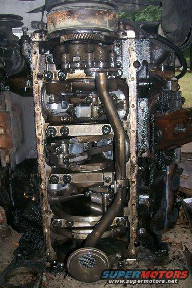 Engine oil pan removed, showing crankshaft and connecting rods. Oil pickup tube visible