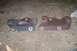 1992 Ford C-350 (Centurion Conversions) - Two exhaust manifold parts, one darker and less rusted than the other, lie on the ground.