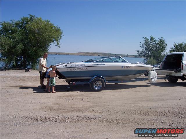 Side view of a 1989 Four Winns boat on a trailer, towed by a white SUV
