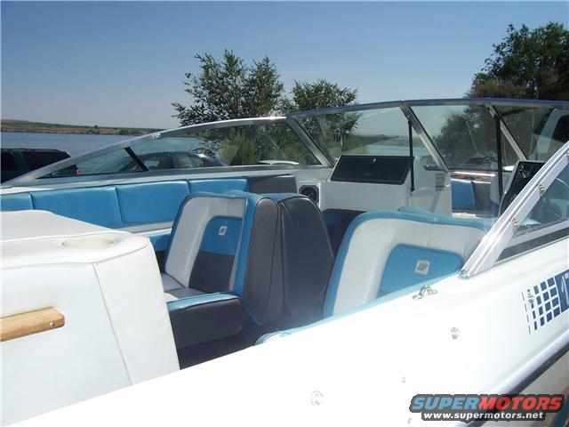 Boat interior with blue and white seats, windshield, and dashboard