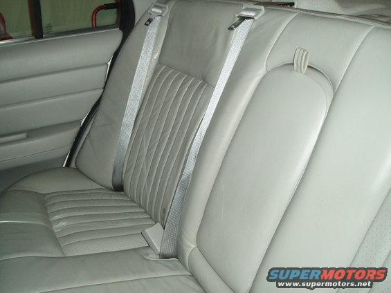 Light gray leather rear car seats with seatbelts and door panel visible