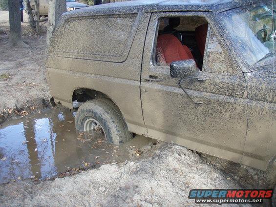 Muddy SUV stuck in a ditch with another vehicle behind it
