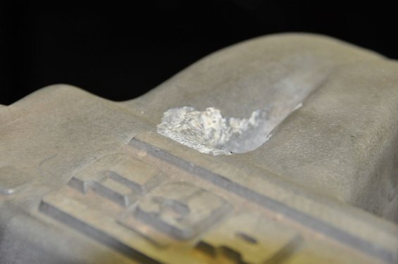 close-up of a damaged metal engine component with a chunk missing