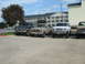 1993 Ford Bronco - Multiple Ford trucks, including two Broncos, are parked in a lot outside a hotel.