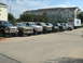 1993 Ford Bronco - A lineup of Ford Broncos and F-Series trucks are parked in a lot outside a hotel, with a Lowe's delivery truck visible.