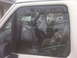 1995 Ford Bronco - The reflection in the window shows trees and a fence, obscuring details of the vehicle's interior.