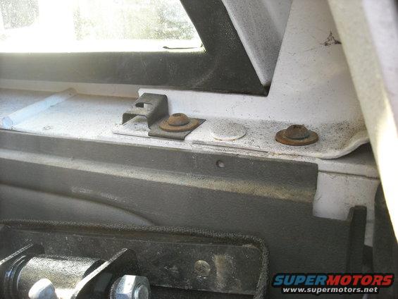 Close-up of rusted mounting hardware and brackets inside a vehicle