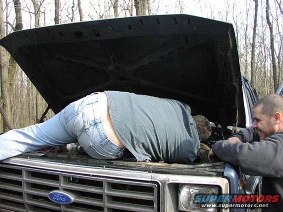 1986 Ford Bronco engine bay with person working on it
