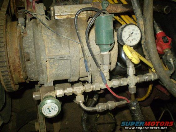 Close-up of engine part with two pressure gauges and green solenoid