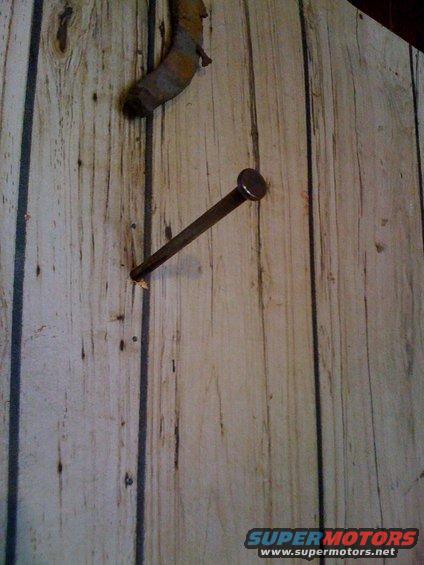 Rusty nail and horseshoe on wood-paneled wall
