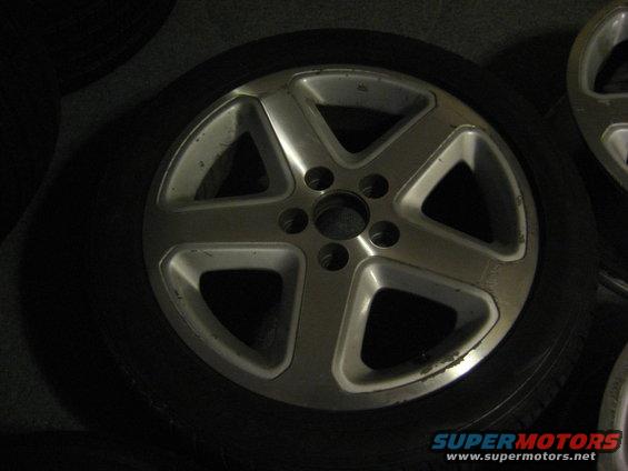 Silver five-spoke alloy wheel with tire, showing some wear