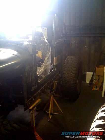 Jeep Wrangler with plastic covering the interior, supported by jack stands