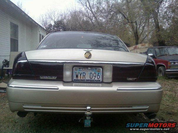 Rear view of a gold 2000 Mercury Grand Marquis with Kansas plates WYR 096. Another vehicle is visible to the right