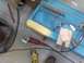1972 Ford Bronco - A blue car door is being prepped for repair with body filler and various tools laid out around it.