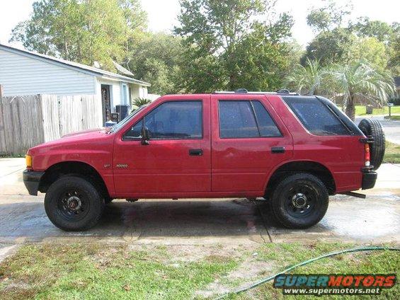 Red 1993 Isuzu Rodeo parked on a concrete driveway with grass and a house in the background