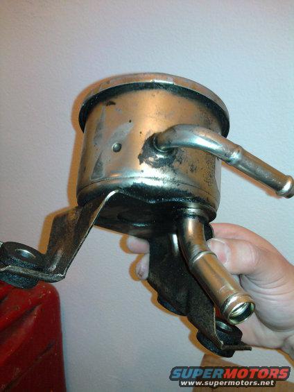 hand holding metal oil filter housing with two hose connections