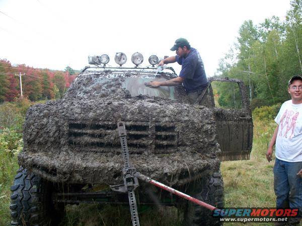 1988 Ford Bronco covered in mud, being cleaned by a person