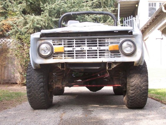 Gray 1973 Ford Bronco front view, showing grille with "FORD" lettering, round headlights, and large tires