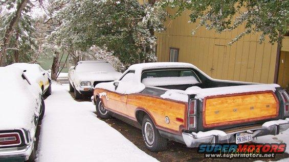 Orange pickup truck parked on a street, another car to its left