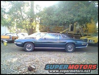 Dark blue 1970s Ford Thunderbird coupe parked outdoors, other vehicles visible