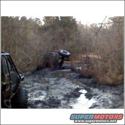 Off-road vehicle stuck in mud, another vehicle partially visible on left