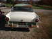 1957 Ford Custom Sedan - The rear of a vintage two-tone sedan, showing its distinctive tail fins and round taillights.