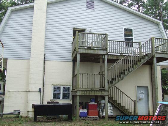 Exterior of a house with a two-story wooden deck and stairs leading up to the second floor