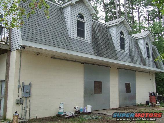 Building with two large metal sliding doors and dormer windows on the roof