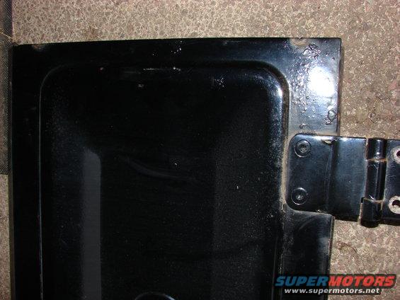 Black metal panel with visible hinge and rust spots