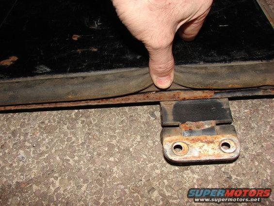 Close-up of a rubber seal being pressed by a finger, with a rusty metal bracket visible. SUPERMOTORS.NET logo at bottom right