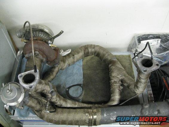 Turbocharger and exhaust manifold assembly wrapped in heat shielding material, with a wastegate attached