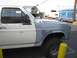 1986 Ford Bronco - This Ford Bronco has a two-tone paint scheme with a gray front fender and white body. A catering truck and a white van are in the backgroun…