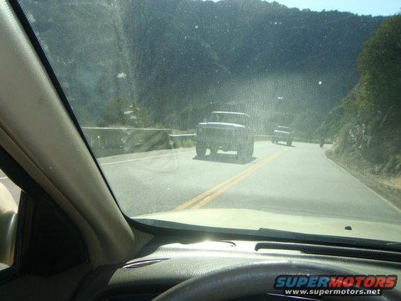 Dark SUV driving on a two-lane road with mountains in the background