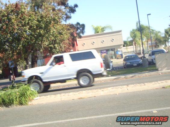 White SUV with lifted suspension and off-road tires, seen from the side