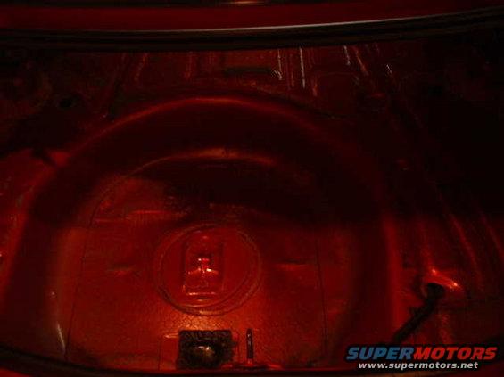 Red car trunk interior with a spare tire well and visible sound deadening material