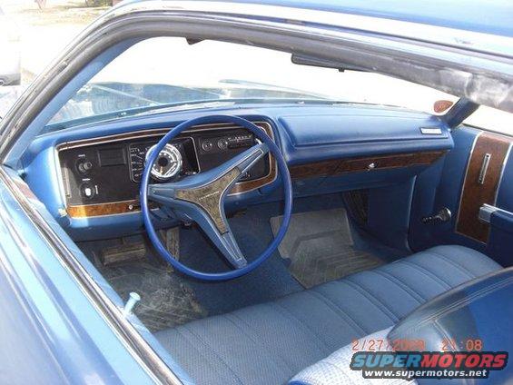 Blue car interior with bench seat, wood trim, and a large steering wheel
