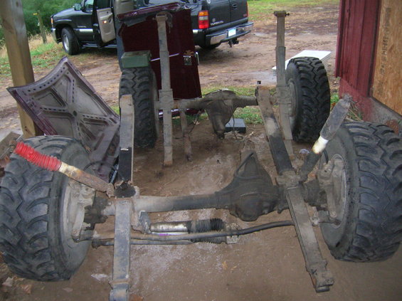 Chassis with suspension and large tires, with a truck in the background