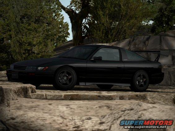 Black sports coupe with a large rear spoiler parked on a rocky surface