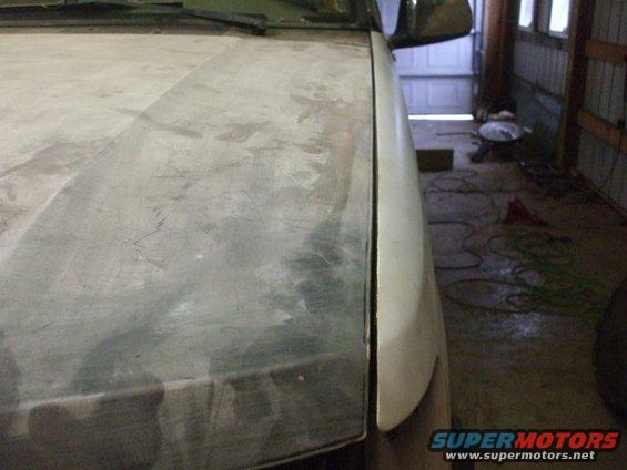 Close-up of a car's hood and fender, showing bodywork in progress